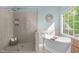 Bright bathroom featuring a glass enclosed shower and soaking tub with views from the large window at 8005 Somerdale Dr, Durham, NC 27713