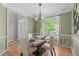 Dining room with hardwood floors, green walls, table set for four, and window providing natural light at 8005 Somerdale Dr, Durham, NC 27713