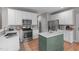 Bright kitchen featuring white cabinets, stainless steel appliances, and a green center island at 8005 Somerdale Dr, Durham, NC 27713