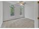 Bright bedroom featuring neutral carpet, a ceiling fan, and two arched windows with tree views at 8022 Hogan Dr, Wake Forest, NC 27587