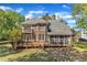 Two story brick home showcasing an expansive deck, screened porch, and mature trees at 8022 Hogan Dr, Wake Forest, NC 27587