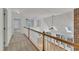 Upstairs hallway featuring a wooden banister overlooking the living room with multiple windows at 8022 Hogan Dr, Wake Forest, NC 27587