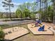 Community playground with swings and slides for children to enjoy, surrounded by trees and a parking area at 8212 Duck Creek Dr, Raleigh, NC 27616