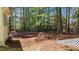 Wooded backyard featuring a stone firepit, lush pine needles, and a charming fence at 903 Oldwyck Dr, Fuquay Varina, NC 27526
