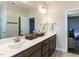Bathroom with double sinks, dark cabinetry and large mirror with an open doorway to bedroom at 937 Matterhorn Dr, Fuquay Varina, NC 27526