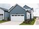 A two-car garage with a white door and blue siding, adding curb appeal to the modern home at 10 Relaxing Way, Pittsboro, NC 27312
