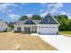 Charming home featuring a two-car garage, stone accents and a manicured lawn under a bright blue sky at 1000 Peedin Rd, Selma, NC 27576