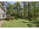 Lush backyard with mature trees, a well-maintained lawn, a deck, and a storage shed, offering a private outdoor retreat at 1013 Whitney Springs Ct, Holly Springs, NC 27540
