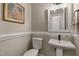 A neutral powder room with a pedestal sink, comfort height toilet, and decorative artwork at 1013 Whitney Springs Ct, Holly Springs, NC 27540