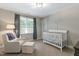 Bedroom with a white crib, comfy chair, and soft gray walls at 1013 Whitney Springs Ct, Holly Springs, NC 27540