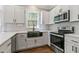 This modern kitchen has white cabinets, stainless steel appliances, and a black farmhouse sink at 1013 Whitney Springs Ct, Holly Springs, NC 27540