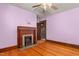 Bedroom with pink walls, fireplace, wood trim, wood floors and ceiling fan at 104 E Wilson St, Mebane, NC 27302