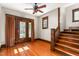 Cozy living room featuring hardwood floors, a ceiling fan, and access to the staircase at 104 E Wilson St, Mebane, NC 27302