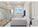 Well-lit bathroom showcasing a glass-enclosed shower, soaking tub, and serene outdoor views at 1093 Trentini Ave, Wake Forest, NC 27587