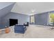A spacious bonus room with blue walls is complete with two armchairs, a TV, a side table, and natural light at 1140 Buttercup Ln, Wake Forest, NC 27587