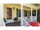 Inviting front porch with wood decking, red azaleas, white railings and posts, and yellow siding at 1140 Buttercup Ln, Wake Forest, NC 27587