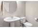 A well lit half bathroom featuring a pedestal sink, toilet, and circular mirror at 126 Elmsford St, Durham, NC 27703