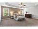 This main bedroom features a tray ceiling, ceiling fan, a bench, and plenty of natural light at 126 Elmsford St, Durham, NC 27703