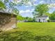 Spacious backyard with a storage building, lush green lawn, patio, and white house surrounded by trees at 12601 Boyce Mill Rd, Raleigh, NC 27613