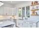 Bright kitchen featuring white cabinets, a modern sink, and floating wooden shelves at 1336 Courtland Dr, Raleigh, NC 27604