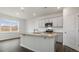Well-lit kitchen boasts gray cabinets, granite countertops, a center island, and stainless steel appliances at 152 Global Ave, Fuquay Varina, NC 27526