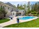 Backyard view featuring a stunning in-ground pool, an outdoor kitchen, and a spacious brick patio with lounge chairs at 16106 Morehead, Chapel Hill, NC 27517