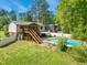 Picturesque backyard showcasing a pool, wood screened in porch, deck, lush lawn, and mature trees at 1624 Cone Ave, Apex, NC 27502
