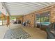 Covered patio with a patterned rug, brick facade, lights, and a sliding door to the interior pool at 1624 Cone Ave, Apex, NC 27502