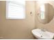 Compact half bathroom featuring a pedestal sink, a decorative mirror, and window for natural light at 2 White Spruce Ct, Durham, NC 27703