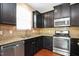 This well-equipped kitchen has stainless steel appliances, dark cabinets, and granite countertops and backsplash at 2 White Spruce Ct, Durham, NC 27703