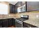 Close-up of kitchen with stainless steel appliances, granite counters, tile backsplash, and dark wood cabinets at 2 White Spruce Ct, Durham, NC 27703