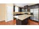 Well-lit kitchen features stainless steel appliances, a large island, dark cabinets, and granite countertops at 2 White Spruce Ct, Durham, NC 27703