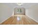 An empty room with hardwood floors and a large window providing plenty of natural light at 207 Ashley Brook Ct, Cary, NC 27513