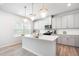 Modern kitchen boasts white cabinetry, quartz countertops, stainless appliances, and elegant pendant lighting at 217 Braeburn Dr, Graham, NC 27253