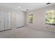 This bedroom features neutral walls and carpet, and a large closet and two windows at 2225 Whitley Dr, Durham, NC 27707