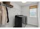 Modern laundry room featuring a front-load washer and dryer, overhead shelving, and a patterned tile floor, offering functionality at 2283 Grants Pass Sta, Apex, NC 27502
