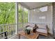 Relaxing covered patio features comfortable armchairs, a wood table, and a serene view of the surrounding greenery and nature at 2283 Grants Pass Sta, Apex, NC 27502
