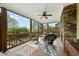 Covered back porch with ceiling fan, stone fireplace, and comfortable wicker furniture at 233 Pointe Park Cir, Holly Springs, NC 27540