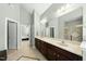 Bright bathroom featuring double vanity, large mirror, walk-in shower, and access to the primary bedroom at 233 Pointe Park Cir, Holly Springs, NC 27540