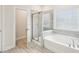 Relaxing bathroom featuring a shower with glass enclosure and separate garden tub with a tiled surround at 2613 Red Spruce Dr, Raleigh, NC 27616