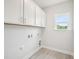 A light and bright laundry room featuring overhead storage cabinets and wood-look ceramic tile flooring at 2613 Red Spruce Dr, Raleigh, NC 27616