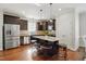 Modern kitchen with stainless steel appliances, dark cabinets, island with stools, and wood floors at 263 Annali Way, Wendell, NC 27591