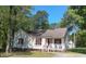 Charming single-story home featuring red shutters, a covered porch, and lush surrounding trees at 334 Cabin Grove Ct, Angier, NC 27501