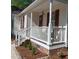 Inviting front porch with white railings and red door, complemented by a brick foundation and manicured landscaping at 334 Cabin Grove Ct, Angier, NC 27501