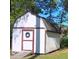 Backyard shed featuring a white exterior with red trim and a wooden ramp at 334 Cabin Grove Ct, Angier, NC 27501
