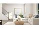 Bright living room with a white sectional, woven ottoman, and a staircase in view at 336 Carolina Springs Blvd, Apex, NC 27539