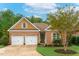 Inviting brick home showcasing a well-kept lawn, two-car garage, and tasteful light green shutters at 4 Calwell Creek Dr, Chapel Hill, NC 27517