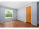 A bedroom featuring wood-look flooring, a window, and a gray paneled wall at 4047 Mistletoe Dr, Burlington, NC 27217