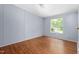 Bedroom featuring wood-look flooring, a window, and a gray paneled wall at 4047 Mistletoe Dr, Burlington, NC 27217