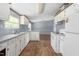 Well-lit kitchen featuring traditional appliances, white cabinets, and wood-look floors at 4047 Mistletoe Dr, Burlington, NC 27217
